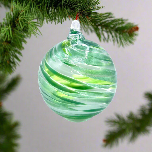 Green and white swirled glass ornament on a light gray background
