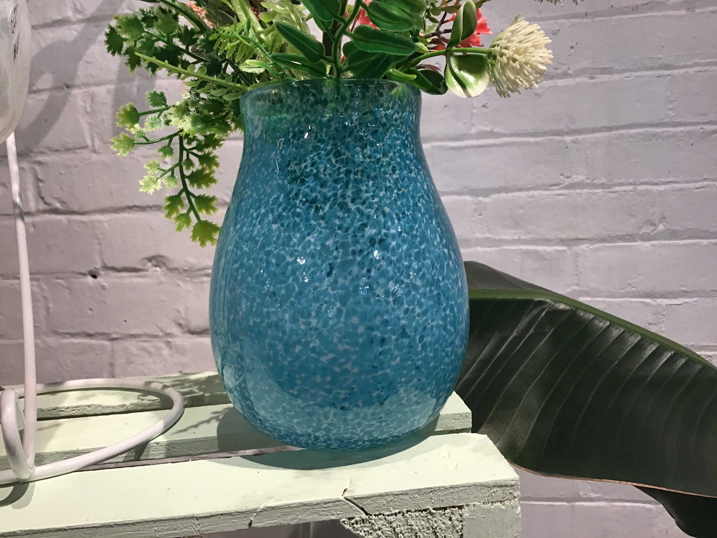 Large blue speckled glass vase with green and white flowers