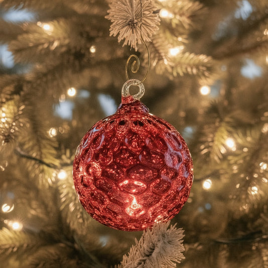 Pink glass ornament hanging on a white stand against a light gray background