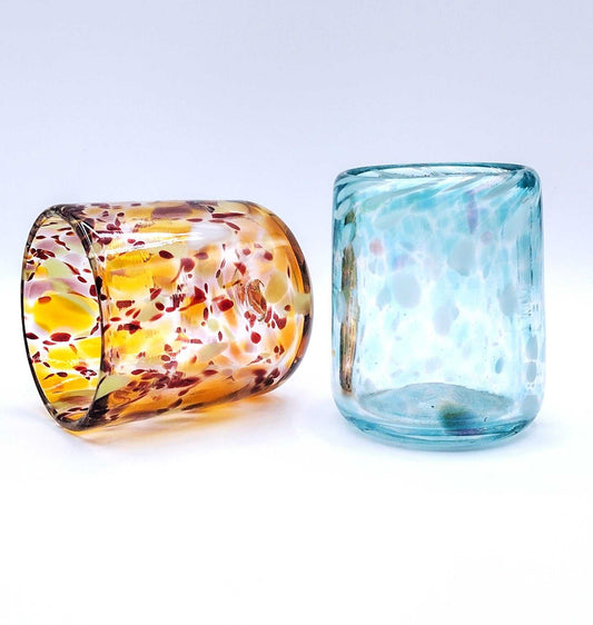 Two handcrafted colorful glass drinking cups showcasing art from Date Night Glassblowing class