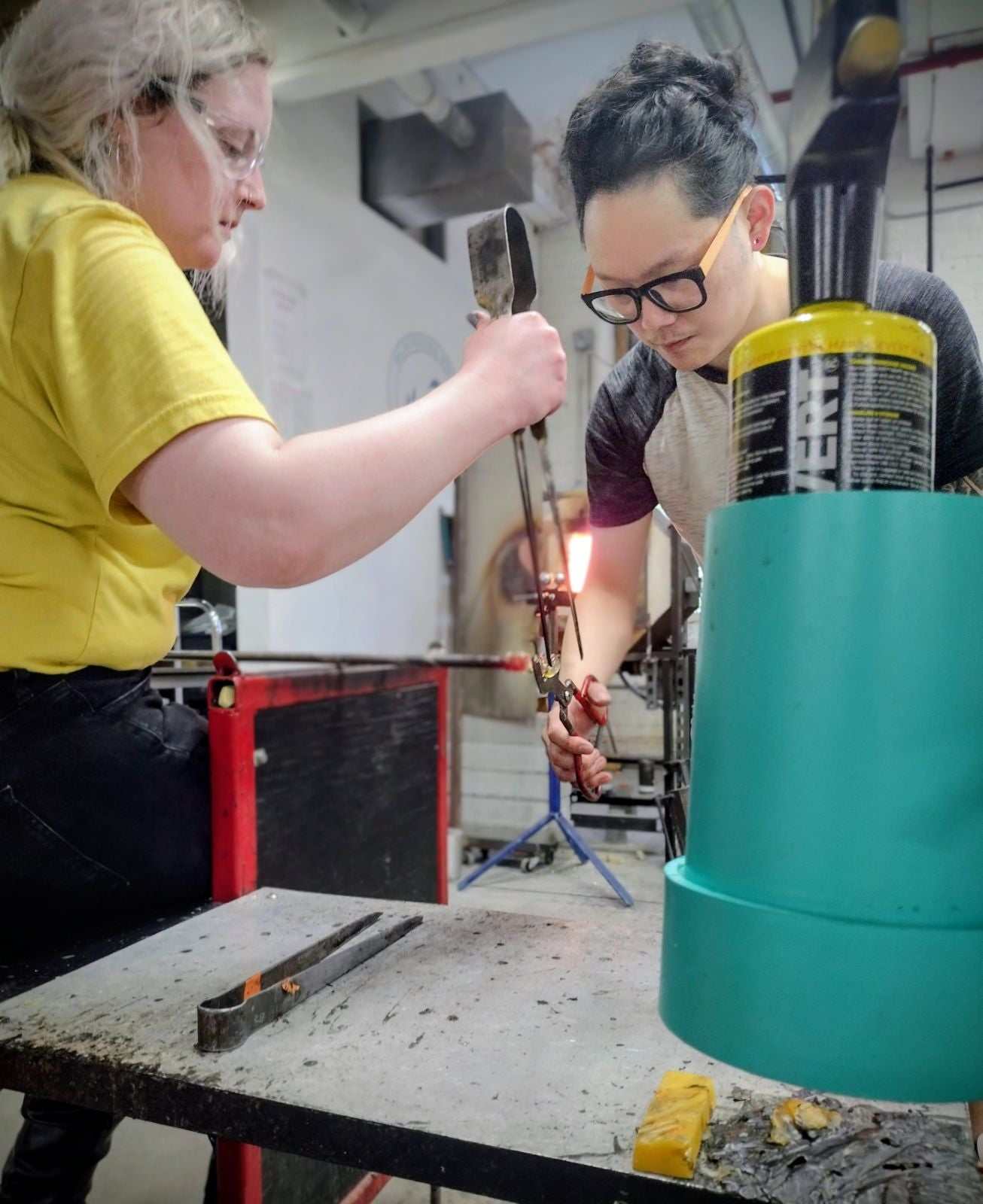 Couple participating in a hands-on date night glassblowing class creating drinking glasses together