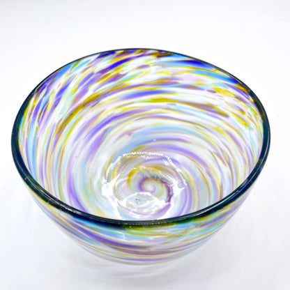 Colorful handblown glass bowl with swirling purple, blue, and yellow patterns made from hot glass