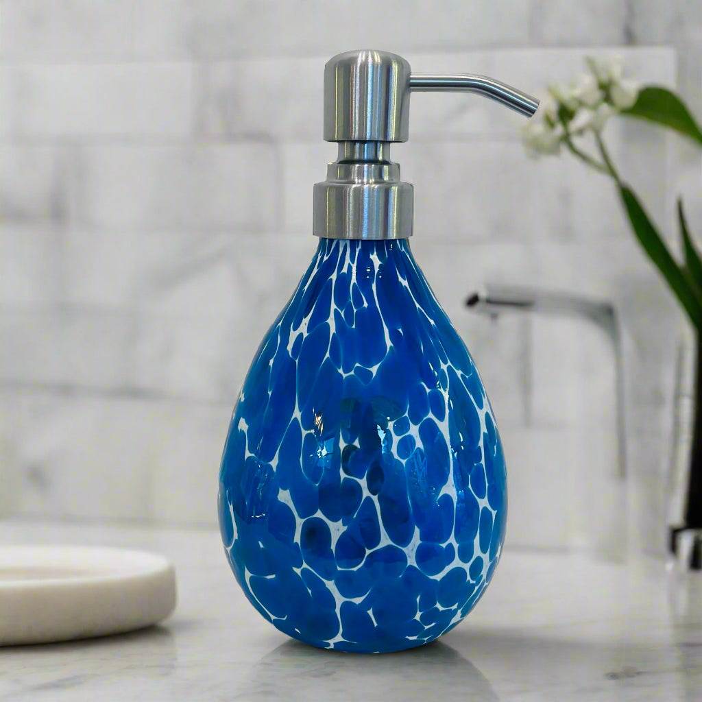 Middle blue  soap dispenser with blue and white pattern and silver pump on bathroom countertop