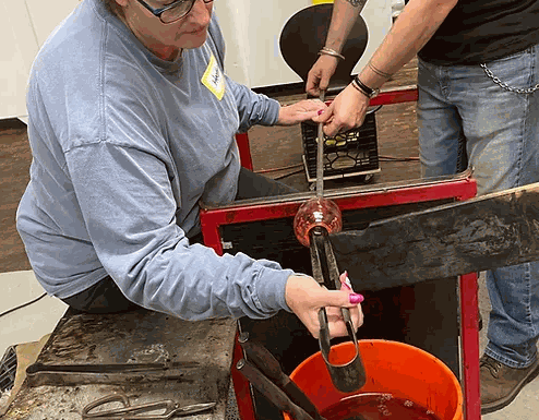 Couple participating in a Date Night Glassblowing class creating a custom drinking glass together
