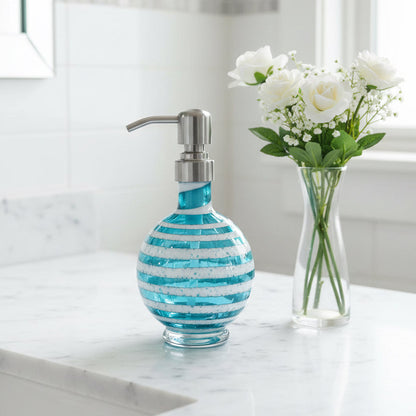 Boho handblown teal blue glass soap dispenser with distressed white spiral and stainless steel pump next to green plant in white pot