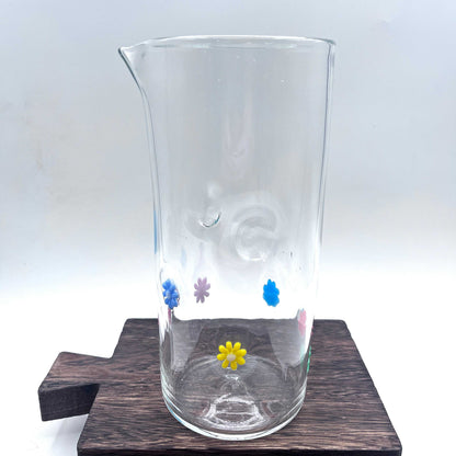 Hand blown stemless glass pitcher with colorful retro flower designs on clear glass