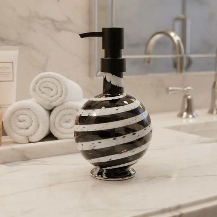 Boho handblown gray glass soap dispenser with white distressed spiral and black pump next to green plant in white pot