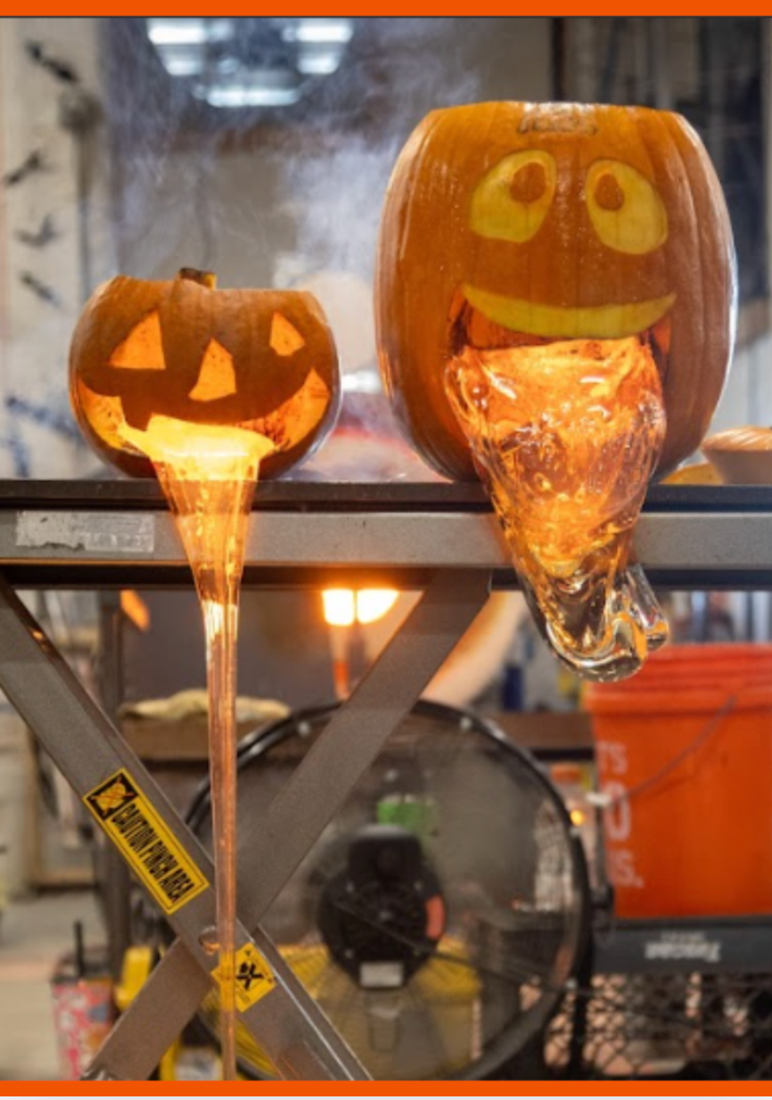 Two lit pumpkin lanterns with carved faces on a metal surface.