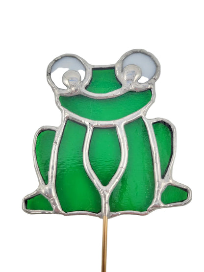 Frog-shaped stained glass window hanging on a gray background