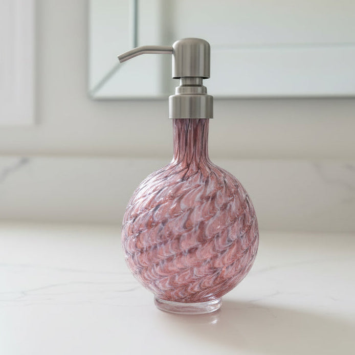 RubyAmethyst mix marbled hand blown glass soap dispenser with stainless steel pump next to small green plant in white pot