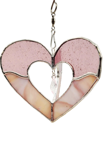 Heart-shaped stained glass window hanging with pink and white colors on a light gray background
